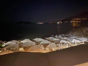 a group of white umbrellas on the beach at night at Porto Palio Beach Hotel in Paleo Tsifliki