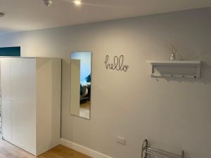 a room with a white wall with a mirror at Modern, Stylish Studio Apartment in Central Northampton in Northampton