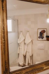 uno specchio che riflette un bagno con asciugamani bianchi sui ganci di Le Clos Serein a Le Beausset