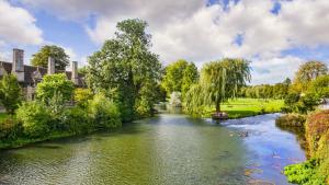 a river in a park with trees and a bridge at Stylish Stamford Centre 2 Bedroom Apartment - St Pauls Apartments - B in Stamford