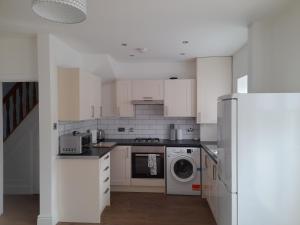 a kitchen with white cabinets and a washer and dryer at Salmestone Stay in Margate