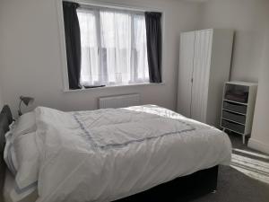 a bedroom with a bed with white sheets and a window at Salmestone Stay in Margate