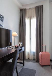 a hotel room with a desk with a computer and a suitcase at Hotel Macià Plaza in Granada