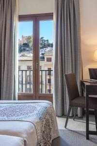 a hotel room with a bed and a desk and a window at Hotel Macià Plaza in Granada
