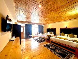 een hotelkamer met 2 bedden en een televisie bij The Country House in Lachung