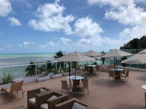 eine Terrasse mit Tischen und Stühlen und Meerblick in der Unterkunft Flat Beira-Mar Blue Sunset in João Pessoa