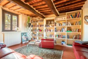 uma sala de estar com uma mesa de vidro e estantes em Casale della Visitazione by VacaVilla em Cantagrillo