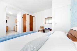 a white bedroom with two beds and a table at BANKO APARTMENTS & Rooms in Rovinj