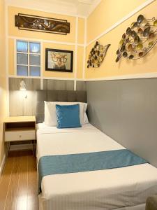 a small bedroom with a bed with a blue pillow at Little Norway Guesthouse - Mactan Cebu International Airport in Mactan