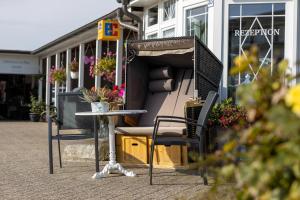 einen Tisch und Stühle vor einem Gebäude in der Unterkunft Familien- und Aparthotel Strandhof in Tossens