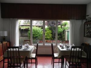 Un comedor con mesas y sillas y un gran ventanal. en Hotel Tritones, en Pinamar