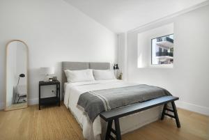 a white bedroom with a bed and a mirror at Villa Sofia Cascais in Cascais