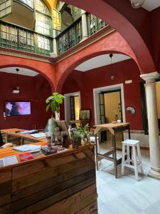 um quarto grande com paredes vermelhas e uma mesa e cadeiras em San Isidoro Hostel Sevilla em Sevilha