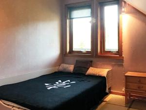 a bed in a room with two windows at Holiday home Nuvsvåg 