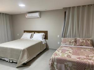 Canto de Roca Turismo e Lazer في Mimoso do Sul: غرفة نوم بسريرين ومكيف