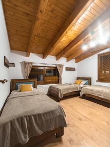 two beds in a room with wooden ceilings at Chalety BUČINA in Oravská Lesná