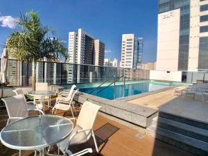 a balcony with tables and chairs and a pool on a building at Metropolitan Flamboyant in Goiânia