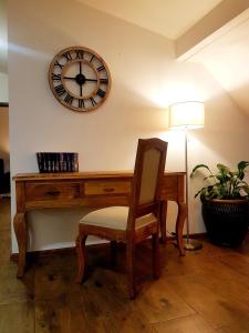 a desk with a chair and a clock on the wall at Flowers in the attic in Żywiec