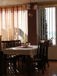 a dining room with a table and chairs and windows at Barátság Panzió - Pensiunea Barátság in Ditrău