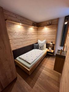 ein kleines Zimmer mit einem Bett in einer Holzwand in der Unterkunft Ferienwohnung Lechraum in Waal in Waal