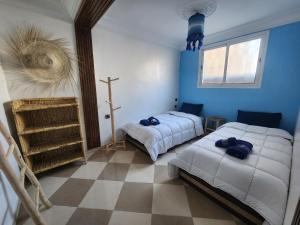 Green Surf House في أغادير: غرفة نوم بسريرين وعلا الحائط صليب