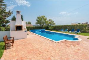 a swimming pool in a yard with chairs and a house at Villa Alegria in Loulé