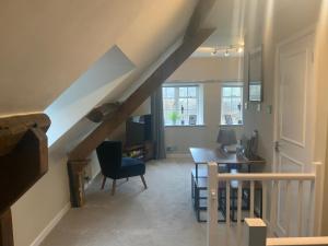 a living room with a staircase and a table and chair at Stable Lodge at Bledington Mill in Bledington