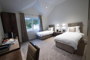 a bedroom with two beds and a tv and a window at Shore Hotel Laxey in Laxey