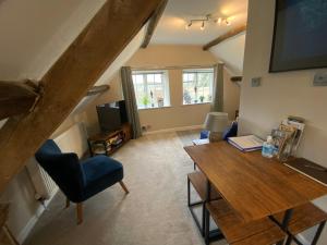 a living room with a wooden table and a television at Stable Lodge at Bledington Mill in Bledington