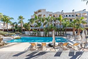 a pool with chairs and umbrellas in front of a building at Luxury Casa con piscina, wifi, 150m dal mare in Miami Platja