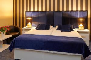 ein Schlafzimmer mit einem großen Bett mit blauer Bettwäsche und einem Stuhl in der Unterkunft Hotel Royal in Gliwice