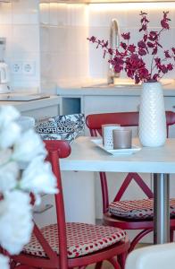 una mesa con sillas rojas y un jarrón con flores en Step8_18, en Westerland