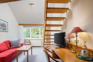 ein Wohnzimmer mit einem roten Sofa und einer Treppe in der Unterkunft Romantischer Seegasthof & Hotel Altes Zollhaus in Feldberg