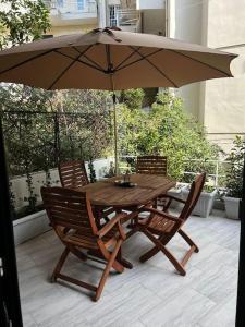 einen Holztisch und Stühle mit Sonnenschirm auf einer Terrasse in der Unterkunft Olivia Luxury Apartment Palio Faliro in Athen