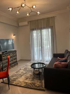 ein Wohnzimmer mit einem Sofa, einem Tisch und einem TV in der Unterkunft Olivia Luxury Apartment Palio Faliro in Athen