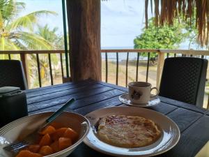 einen Tisch mit einem Teller Essen und einer Tasse Kaffee in der Unterkunft Bungalow Palmar del Viento in Moñitos