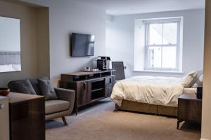 a bedroom with a bed and a tv and a chair at Shore Hotel Laxey in Laxey