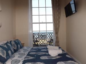 a bedroom with a bed and a large window at The Edenhurst Guesthouse in Weymouth