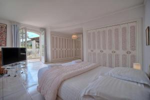 Habitación blanca con 2 camas y TV de pantalla plana. en IMMOGROOM- Top of villa 200m2 - Garden - Pool - Sea view - Parking - Wifi, en Vallauris