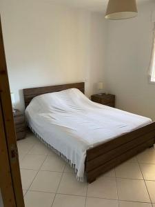 um quarto com uma cama com uma colcha branca em Appartement T3 Les eucalyptus em L'Île-Rousse