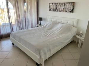 a large white bed in a bedroom with a window at Appartement T3 Les eucalyptus in LʼÎle-Rousse