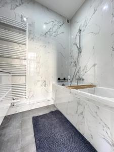 een witte badkamer met een bad en een wastafel bij Cosy Apartment Brussels - Palais Royal in Brussel