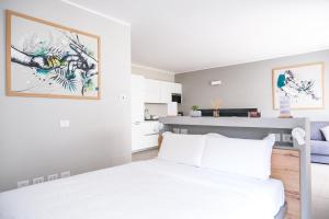 a white bedroom with a bed and a kitchen at Viam Imbriani Suites in Rome