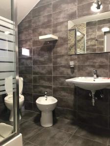 a bathroom with a sink and a toilet and a mirror at camere de închiriat livada cu meri in Căpăţîneni-Ungureni