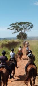 um grupo de pessoas andando a cavalo em uma estrada de terra em Hotel Fazenda Bela Vista em Dourado