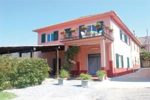 ein rotweißes Gebäude mit einem Balkon und Pflanzen in der Unterkunft Green Quiet Affittacamere in Pignone