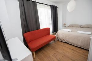 a red chair in a bedroom with a bed at 4 Mares Apartamentos A in Loredo