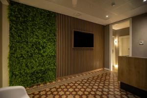 una pared verde en un vestíbulo con TV en Fontanella By BCN URBAN Rooms, en Barcelona