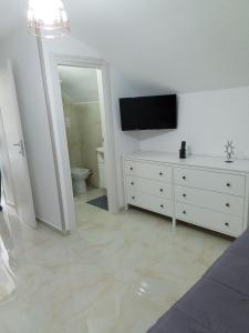 Dieses weiße Zimmer verfügt über einen TV und eine weiße Kommode. in der Unterkunft casa italia in Neapel