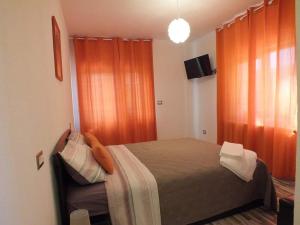 een slaapkamer met een bed met oranje gordijnen en een televisie bij livada-cu-meri in Căpăţîneni-Ungureni